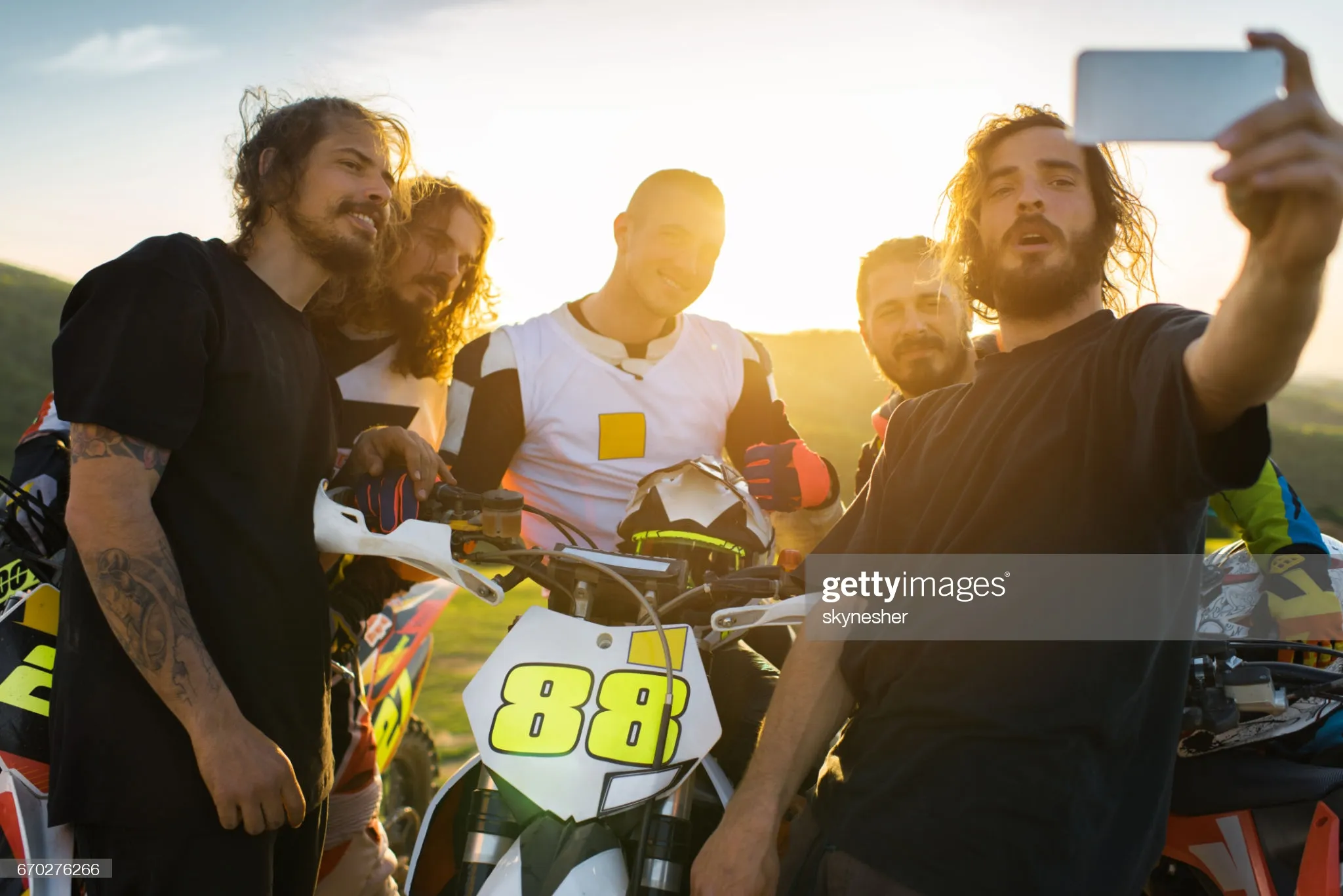 Team of dirt bike racers taking selfie at sunset. : Stock Photo