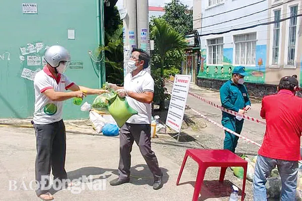 Thầy giáo Đinh Văn Trung, Trường THPT Nguyễn Trãi (TP.Biên Hòa, thứ 3 từ phải qua) phân phát nhu yếu phẩm cho người dân trong khu vực phong tỏa. 